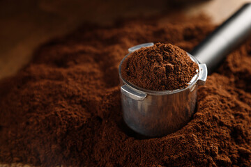 Black ground coffee in coffee holder on coffee background with texture