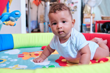 Obraz premium Baby lying on a colorful play mat on the floor at home.