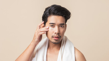 Asian men with mustaches apply eye cream to reduce dark circles on brown background. Young man...