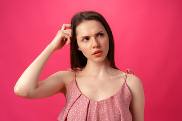 Fototapeta premium Portrait of young woman thinking and wonder against pink background