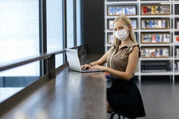 Beautiful woman with blond hair wear medical mask using with computer laptop at office table. professional freelancer in workplace.