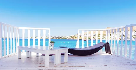 Foto op Plexiglas Relaxing Rattan Sunbed and White Wooden Table with Sea View .Private Beach above the Sea © boryanam