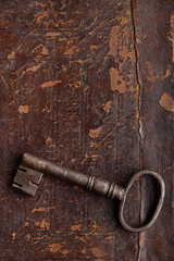 Old metal door key on a brown ancient surface, studio shot.