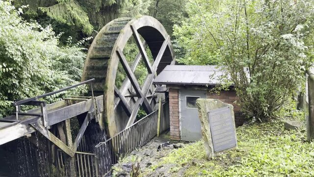 the wheel of an old water mill is driven by the water of a stream