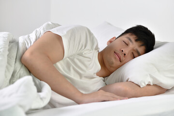 Obraz na płótnie Canvas Handsome Young Asian man sleeping in bed