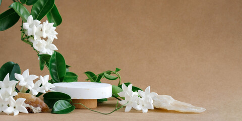 Creative minimal scene natural stones,green leaves and white flowers. cylinder wood podium on beige...