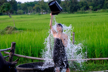 At the countryside, a rural girl is taking a shower from a traditional groundwater source.