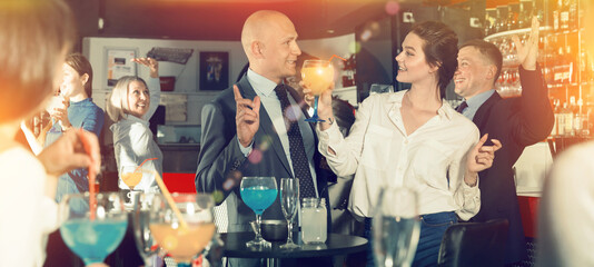 Smiling man and woman drinking alcohol and having conversation on corporate party