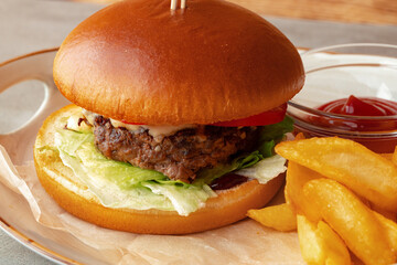 Fresh burger and potato wedges on gray wooden background