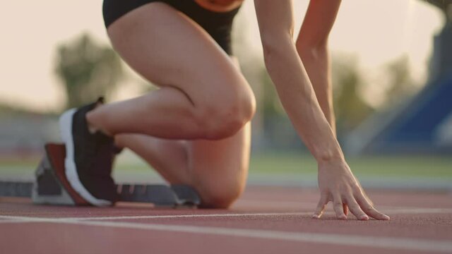 Caucasian young brunette woman shit for a run in the stadium comes up to the running sides and starts the sprint race in slow motion
