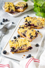 Shortbread bar cookies with blueberries on a serving board on a light gray kitchen table. Delicious homemade sweet pastries