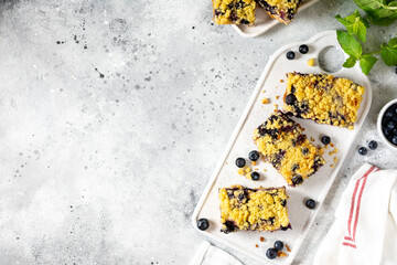 Shortbread bar cookies with blueberries on a serving board on a light gray wooden kitchen table top view. Delicious homemade sweet pastries