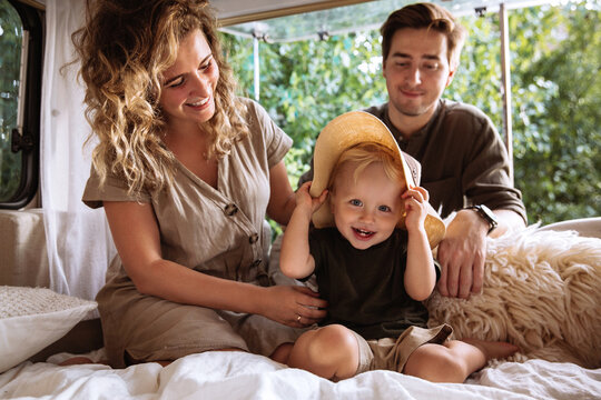 Loving parents enjoy spending time with little kid boy travelling together on camper rv. Happy young family on road trip vacation: caring mom and dad bonding cuddle with small child in caravan trailer