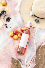 Summer beach picnic on the coast. Bottle of rose wine, fruits, summer accessories. Romantic party concept. Top view - 450012178