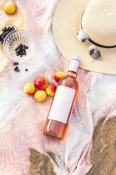 Summer beach picnic on the coast. Bottle of rose wine, fruits, summer accessories. Romantic party concept. Top view