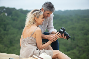 couple on a sand dune reviewing photographs on their camera