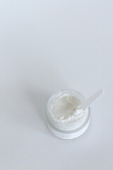 Moisturizing cosmetic cream with eucalyptus stands on neutral background with milk splash
