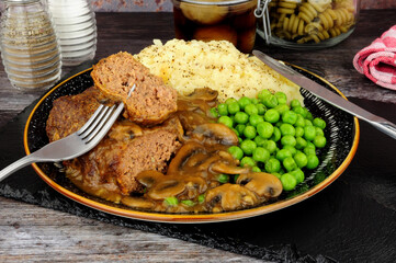 Salisbury steak meal with mashed potato, peas and mushroom sauce