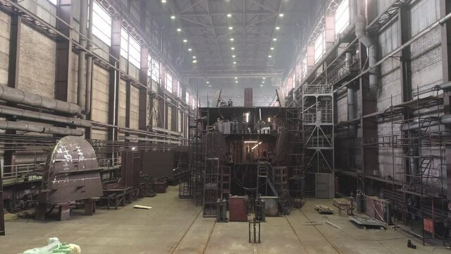 Restoration of huge old metal multilevel vessel surrounded by high scaffolds in light spacious repairing dock
