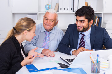 Fototapeta premium Employees are writing financial reports and discussing with mature boss in the office.