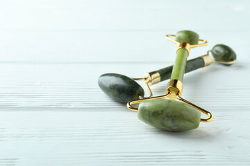 Green face rollers on white wooden background