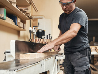 A carpenter works on a board sanding machine