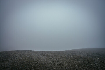 Black stone field in dense fog in highlands. Empty stone desert in thick fog. Zero visibility in...