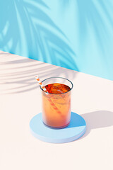 Cocktail drink in glass with ice and straw on blue background with tropical leaf shadows, 3d render