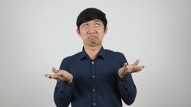 Asian man shrugs shoulders hand up dont care face white background,Unhappy and up to you concept