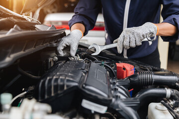 Fototapeta premium Automobile mechanic repairman hands repairing a car engine automotive workshop with a wrench, car service and maintenance,Repair service.