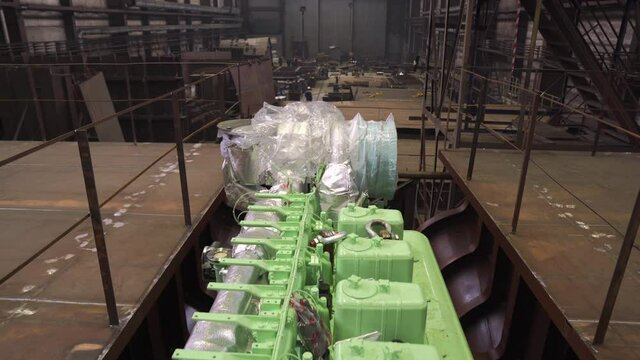 Modern bright green powerful engine in hold of antique renewable ship in light spacious dry repairing dock closeup
