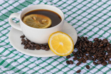 Coffee in white cup with roasted coffee beans and lemon.