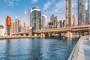 Scenic view of high skyscrapers with offices, hotels and residential buildings in UAE. Road over the bridge and flyover passes through the Dubai Creek Canal