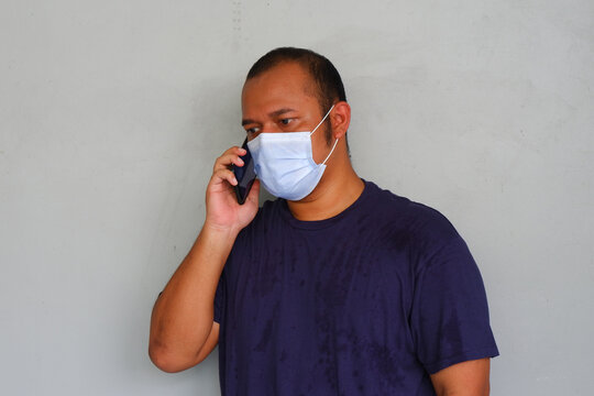 Young asian man wearing medical mask and make phone call