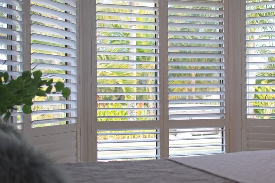 Luxury white indoor plantation shutters in bedroom - selective focus