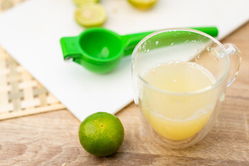 lime on a wooden table for squeezing lemon juice in a glass, selective focus.