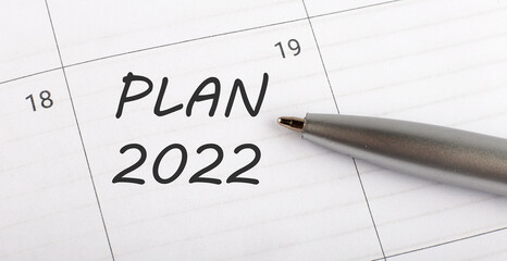 Text PLAN 2022 on calendar planner to remind you an important appointment with a pen on isolated white background.