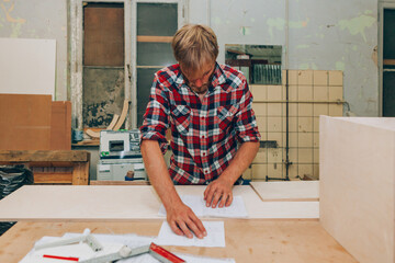 Young designer looking project plans at carpentry workshop studio