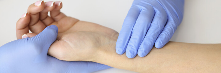 Doctor measuring pulse on patient forearm near empty syringe and medication closeup