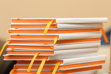 Stack of several white notebooks with orange pages. Stationery