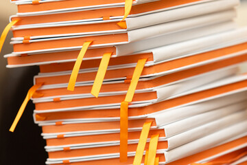 Stack of several white notebooks with orange pages. Stationery