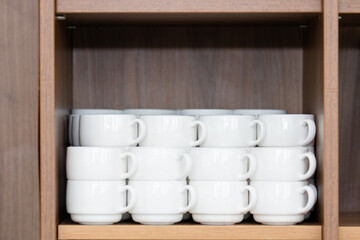 White cups stacked on a shelf in a hotel. Coffee mugs