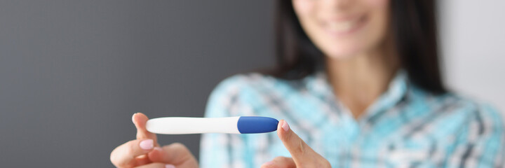 Happy woman holding pregnancy test in her hands and smiling closeup