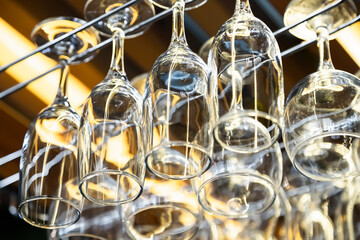clean wine glasses hang over the bar. Glass, utensils, objects.