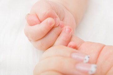 A close up of a baby hand holding a mother hand