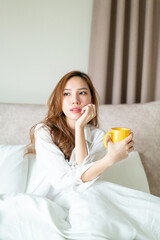 portrait beautiful woman wake up and holding coffee cup or mug on bed