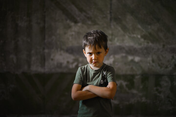 a five-year-old boy, angry and upset, stands against a dark wall
