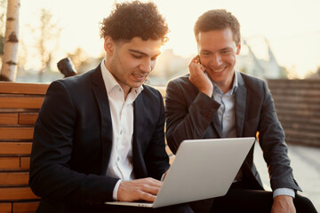 Two male entrepreneurs are discussing interesting ideas for the future project. Friends, managers and colleagues are creating a new startup. Business suits, work near the office on the street.