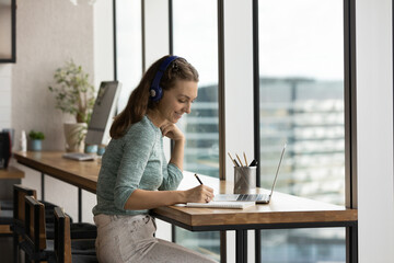Happy gen Z student girl in headphones studying online, attending virtual class, listening webinar...