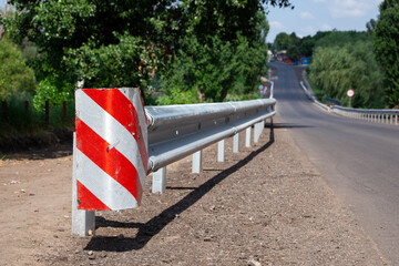 red road reflectors along the road. metal road fencing of barrier type, close-up. Road and traffic safety. reflective paint on sign. Median steel barrier